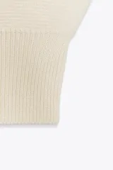 Chaleco de punto liso con escote en pico y diseño sin mangas. Presenta un corte corto con acabados en rib en el cuello, las sisas y el ruedo.