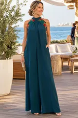 Mono largo de seda color verde oscuro, con escote halter y detalles de apliques bordados florales en los laterales del cuello y hombros.