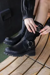 Bota corta de cuero negro con hebillas y cierre lateral.