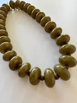 Collar de cuentas redondas y aplanadas con efecto marmolado en tonos grisáceos, con cierre metálico dorado.