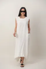 Vestido largo de lino color blanco, sin mangas, con cuello redondo, bolsillos laterales y detalles desflecados en sisas y dobladillo.