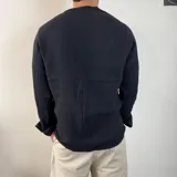 Camisa de manga larga confeccionada en muselina de algodón, con cuello mao y cierre frontal de tres botones. Presenta una textura arrugada característica del tejido y puños con opción de arremangar.