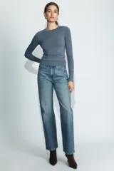 Jersey de punto liso color negro, con cuello redondo y manga larga. Presenta una hilera de cuatro botones dorados decorativos en el puño de cada manga.