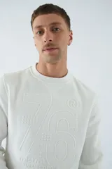 Buzo blanco de algodón con cuello redondo, mangas largas y logo y arte en relieve en el frente.