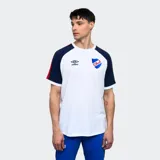 Remera de algodón blanca con mangas cortas ranglan azul marino con una franja roja en el hombro. Tiene el logo de Umbro bordado en el pecho y el escudo del Club Nacional de Football.