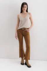Pantalón de jean color marrón óxido, tiro medio, corte ajustado en muslos y ligeramente acampanado en la parte inferior (bootcut/flare), con bajo desflecado.