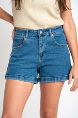 Short de denim azul de tiro medio, con bolsillos delanteros y traseros, cierre de botón y cremallera, y botamangas con dobladillo.