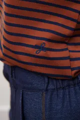 Remera de manga larga con diseño de rayas horizontales en azul y blanco, destacada por un cuello redondo en color bordó con costuras a la vista.