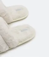 Pantufla cerrada de diseño acolchado con gajos, confeccionada en tejido de textura felpuda suave, con suela de goma termoplástica.