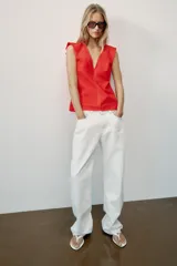 Top rojo de popelín con escote en V pronunciado, mangas sisa y pespuntes en contraste. Cuenta con tirantes finos cruzados y lazada en la espalda.