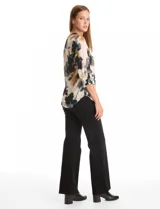 Blusa de gasa con estampado floral en tonos blanco y negro, cuello a la base con escote en V y cierre frontal parcial con botones. Presenta mangas tres cuartos con puños rectos.