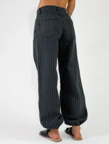 Pantalon de denim azul con diseño de rayas verticales blancas, de corte holgado y estilo relajado.