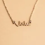 Collar de cadena fina con dije calado que forma un nombre en tipografía cursiva, confeccionado en plata 925.