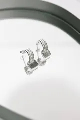 Aros de plata formados por tres aros delgados paralelos que sostienen una placa cuadrada con acabado texturizado.