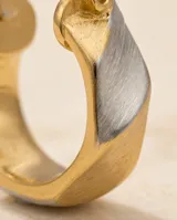 Aros tipo argolla pequeña con diseño de superficie texturizada y acabado bicolor en tono dorado y plateado.