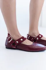 Ballerinas de cuero bordó con puntera cuadrada, diseño destalonado y tira en el empeine decorada con tachas metálicas.