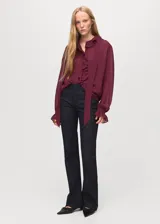 Blusa de viscosa color bordó, con diseño de volantes frontales, cuello redondo con detalle de fular integrado y mangas largas con puños abotonados.