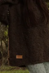 Sweater marrón de tejido de punto grueso con mangas largas y costuras blancas decorativas.