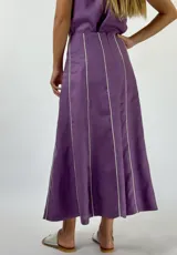 Pollera larga color beige con paneles verticales y ribetes blancos.