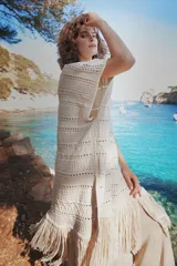 Chaleco largo de tejido de punto color azul verdoso, sin mangas y con flecos en el ruedo. Presenta calados con diseño geométrico.