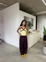Pantalón de corte amplio y relajado en color uva, con diseño de solapas cruzadas en la cintura y cierre frontal. Presenta una silueta holgada y fluida.