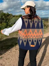 Chaleco tejido sin mangas con escote en V, presenta un diseño geométrico de rombos en tonos azul marino, naranja y gris. Confeccionado en tejido de punto liviano, posee terminaciones acanaladas en el cuello, sisas y ruedo.
