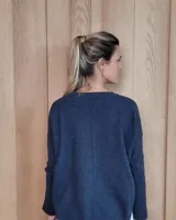 Sweater de punto color beige, con cuello en V, manga larga con puños acanalados y diseño holgado.