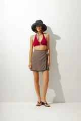 Falda corta tipo pareo con diseño envolvente, confeccionada en tela con estampado de rayas verticales en tonos tierra. Cuenta con un lazo lateral para ajuste y un borde inferior con detalle de costura en contraste.