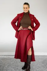 Pollera midi de corte irregular con diseño de estampado cuadrillé en tonos rojo y negro. Presenta un acabado con flecos en el borde y una abertura lateral que deja ver la pierna.