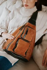 Bandolera de cuero color beige con detalles en bordó. Tiene correa ancha regulable para llevar cruzada al cuerpo, cierre principal con cremallera y dos bolsillos frontales con cierre.