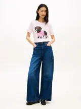 Remera de manga corta color rosado de Tommy Hilfiger, con cuello redondo y diseño casual. En el centro del pecho cuenta con un gráfico bordado de un perro salchicha con un suéter a cuadros rosado y blanco, y flores en la boca.