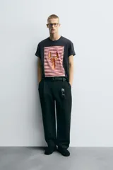 Camiseta azul marino de corte relaxed fit, cuello redondo y manga corta. Presenta un parche rectangular estampado con rayas horizontales rojas y blancas, y un dibujo de una langosta en el centro.