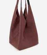 Cartera hobo grande marca Satinato, confeccionada en cuero con textura natural y color marrón oscuro. Presenta un diseño amplio y suave de estilo contemporáneo, con asas de hombro integradas y cierre interno con mosquetón.