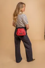 Bandolera pequeña de diseño moderno, confeccionada en tafeta liviana y resistente. Cuenta con cierre superior, correa ancha ajustable y logo frontal de la marca.