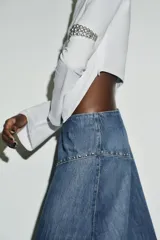 Camiseta de cuello barco y manga larga con diseño asimétrico en el bajo. Presenta un corte entallado con cierre lateral mediante cremallera oculta.