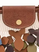 Cartera de red grande Longchamp de la línea Le Pliage Filet Camo, con diseño de red decorado con apliques de flores y solapa con asas de cuero marrón.