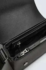 Bandolera negra con textura grabada, correa ajustable, monedero extraíble, compartimento principal con solapa imantada, bolsillo interno con cierre y bolsillo frontal con cierre.