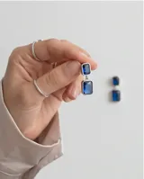 Caravanas colgantes de acero con diseño de doble rectángulo y piedras azules engarzadas.