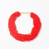 Collar tipo gargantilla compuesto por múltiples hilos de pequeñas cuentas de vidrio en color rojo intenso, con cierre de mosquetón y cadena de extensión en tono dorado.