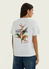 Remera blanca de manga corta y cuello redondo, confeccionada en algodón, con un pequeño estampado floral en el pecho.