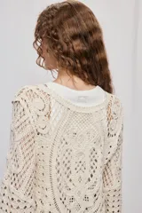 Sweater corto color crudo de manga larga, confeccionado en crochet calado con diseño artesanal y silueta amplia.