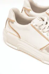 Championes estilo urbano con combinación de cuero metalizado en tono oro y off white, con detalles de costuras pespunteadas, cordones al tono y suela de goma chunky.
