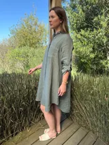 Vestido camisero color beige claro, de lino 100% natural, con botones de nácar, bolsillo delantero y mangas 3/4 con botón para recogerlas. Diseño asimétrico, más largo en la parte trasera.