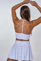 Conjunto deportivo compuesto por un top de escote en V con breteles finos y una pollera corta tableada con cintura alta.