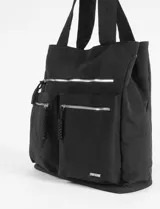Bolso tipo shopper de gran tamaño en color negro, confeccionado en poliéster. Presenta un compartimento principal con cierre, dos bolsillos frontales con cierre y un bolsillo adicional superior con cierre. Incluye correas anchas para llevar al hombro y detalles de tiradores de cordón trenzado.