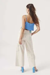 Blusa de satén color crema con escote drapeado y tirantes finos, de corte corto.