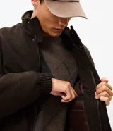 Campera bomber puffer de color marrón oscuro, confeccionada en poliéster con acabado texturizado. Presenta cuello alto, cierre frontal con cremallera, puños y ruedo elásticos.