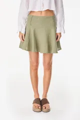 Minifalda color marrón oscuro, confeccionada en lino italiano, con diseño de cintura baja con caderín y bajo acampanado. Cierre invisible en el lateral.