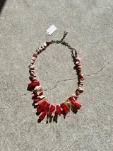Collar hecho a mano con cuentas de coral rojo y nácar blanco, engarzadas en cadena metálica plateada.
