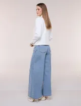 Camperita corta blanca de punto elastizado, con cuello camisero, cierre frontal completo y mangas largas con puños anchos abotonados.